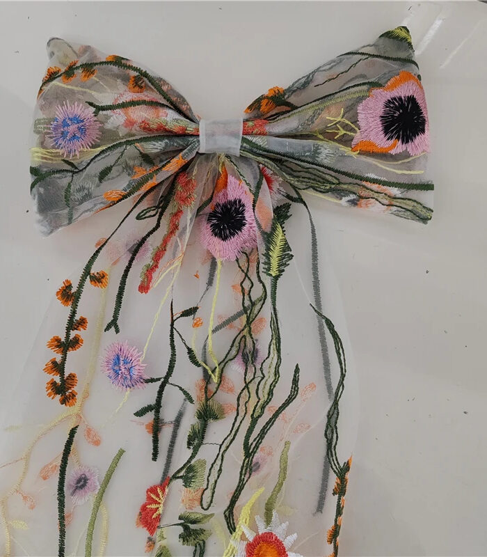 The Poppy Bow, a wildflower embroidered wedding hair bow with veil tails on a comb