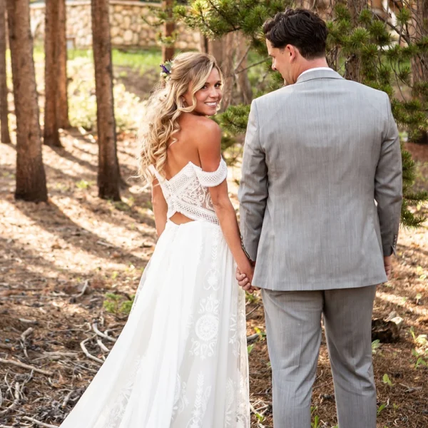 Back view of a draped off-shoulder boho wedding dress with crochet lace and waist cutouts