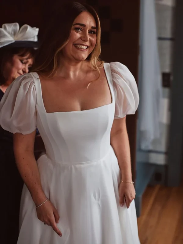 Close view of the square neckline and sheer organza puff sleeves on an ivory bridal gown