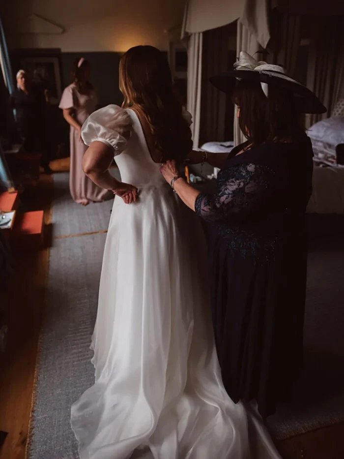 Back of a simple organza A-line wedding dress being fastened before the ceremony