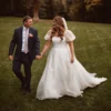 Bride and groom walking on grass, organza A-line wedding dress with sweeping train