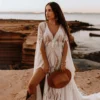 Bride seated outdoors in V-neck lace wedding dress with front slit