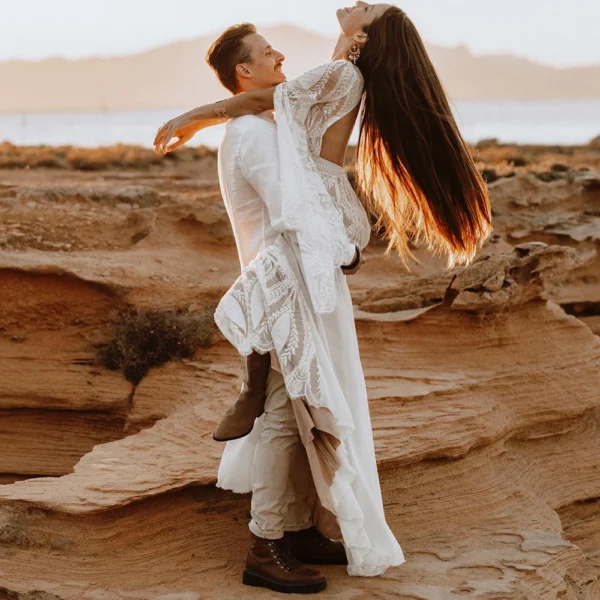 Couple celebrating outdoors with bride in bell-sleeve lace wedding dress