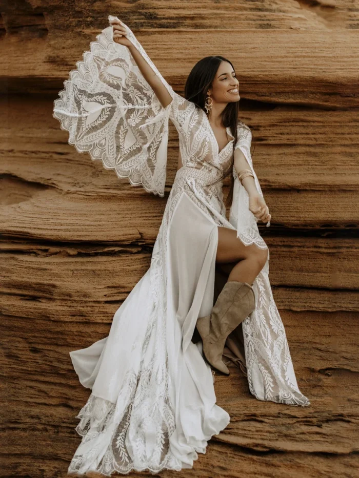 Bride wearing the Sandstone Serenade boho lace wedding dress with bell sleeves against sandstone cliffs